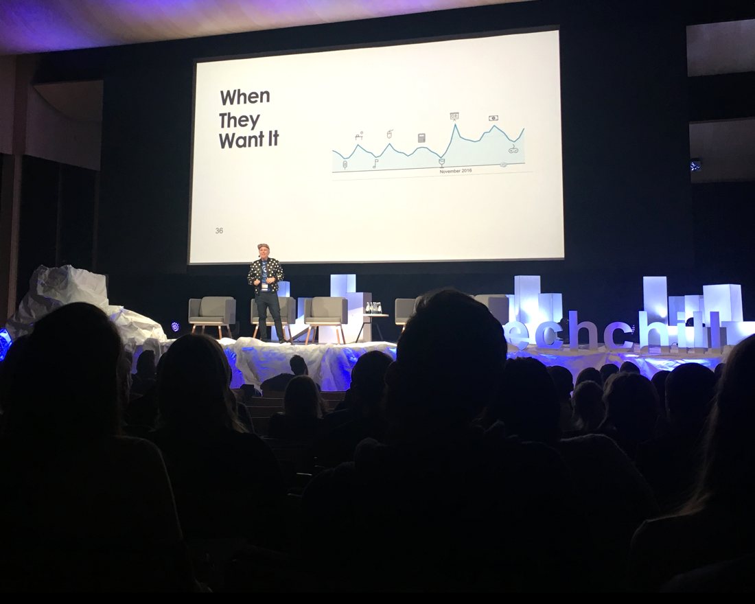Lauren Proctor on stage at TechChill in Riga, presenting a slide titled When They Want It to a full auditorium.
